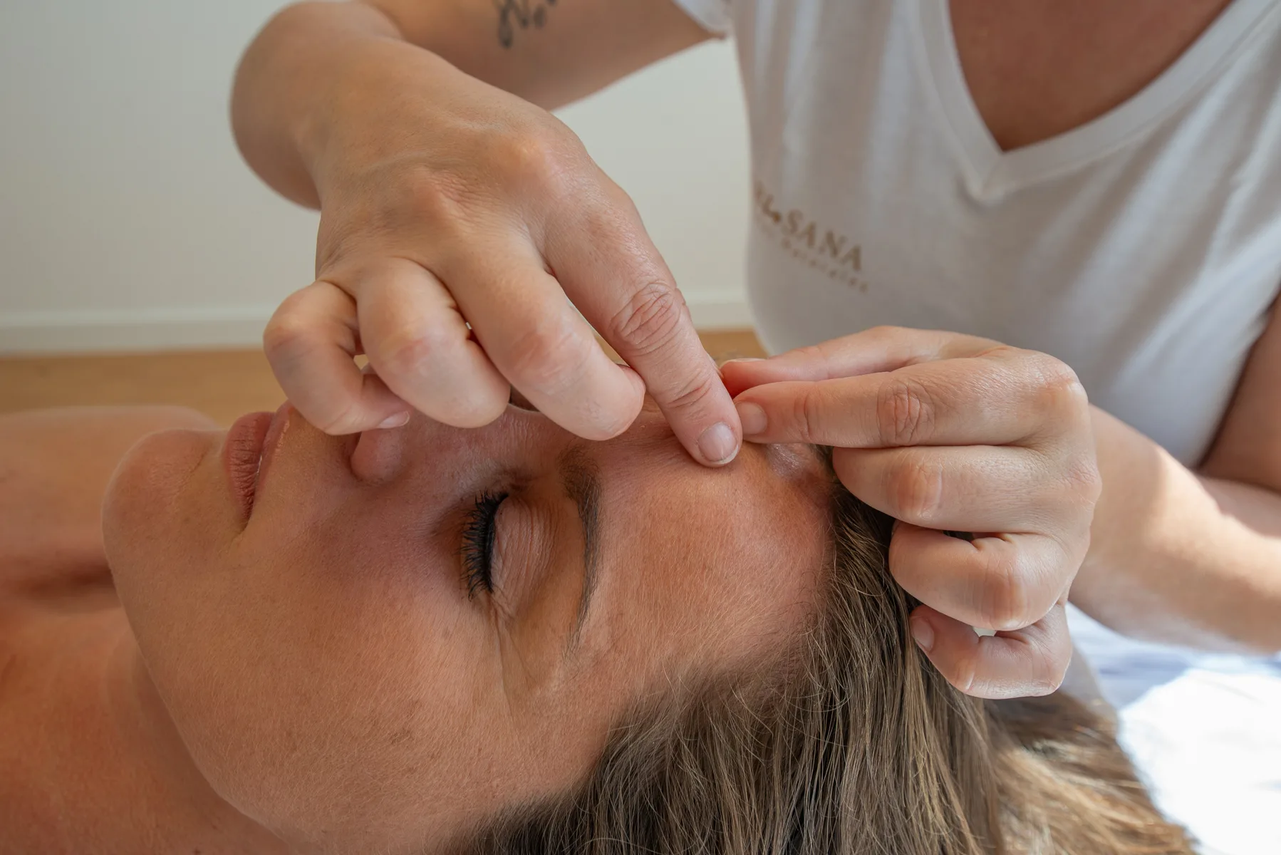 Chiropractor performing facial massage for client